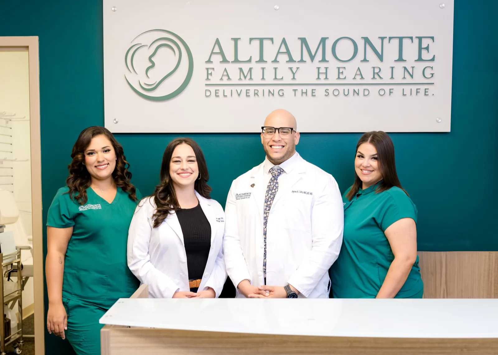 Francesca, Toni, Jaysee and Grace behind the front desk, under the Altamonte Family Hearing sign