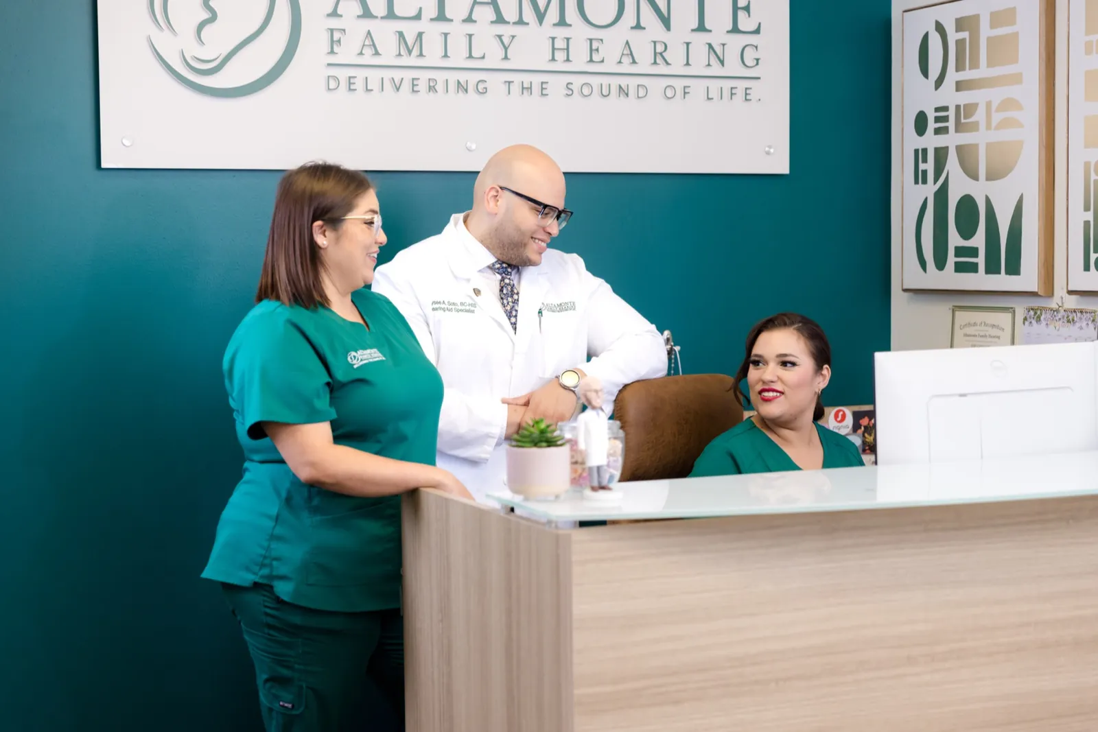 Grace, Jaysee and Francesca at the front desk under the Altamonte Family Hearing sign