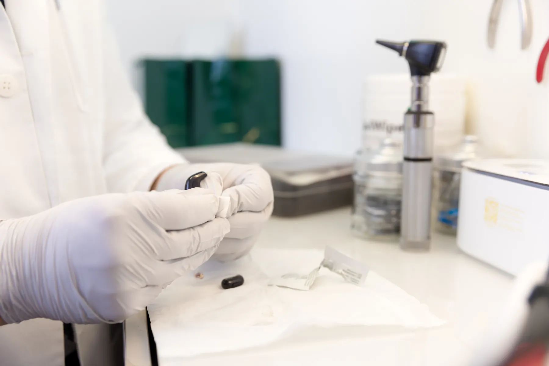A hearing aid being repaired at the bench, in gloved hands