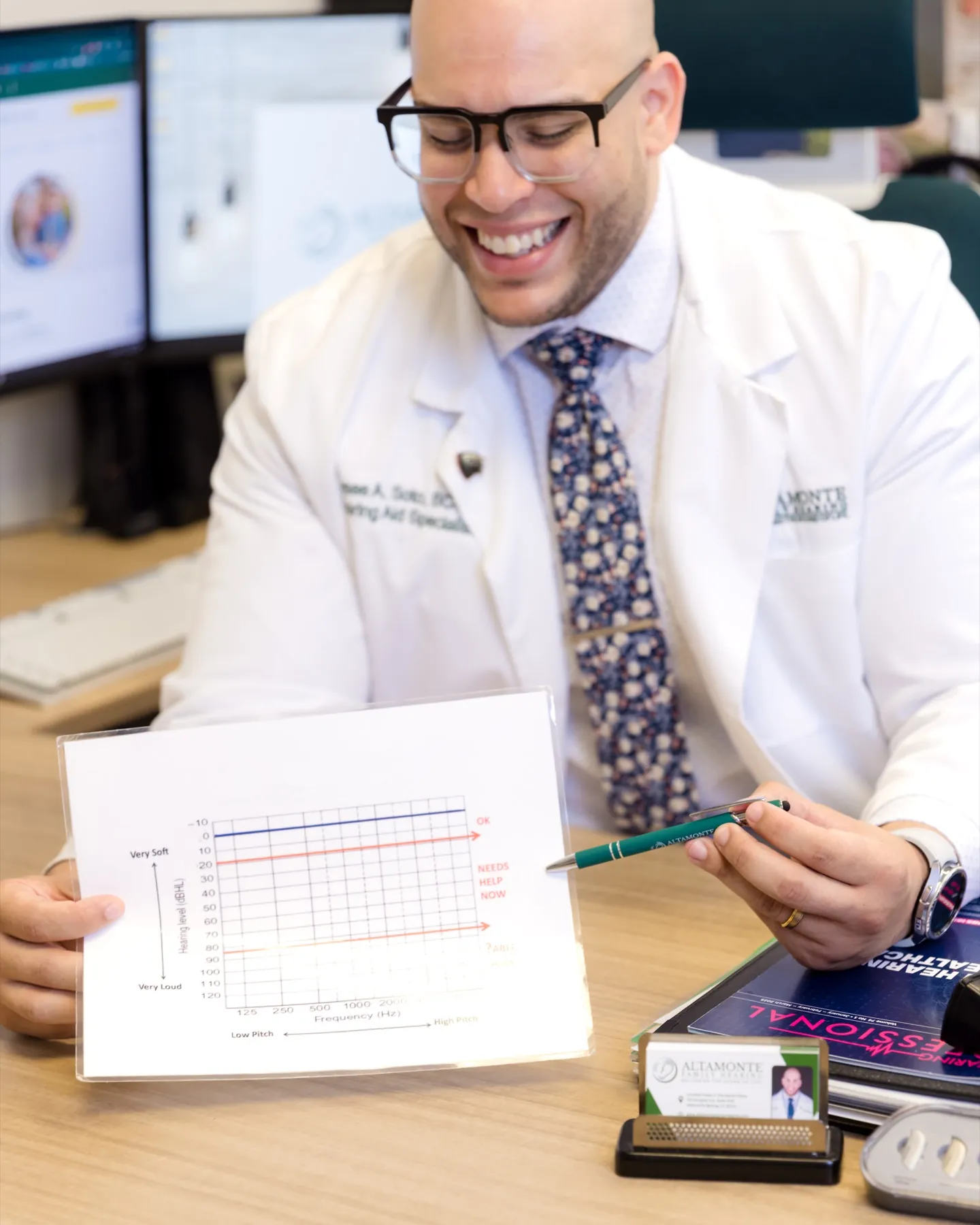 Jaysee laughing while explaining an audiogram at his desk