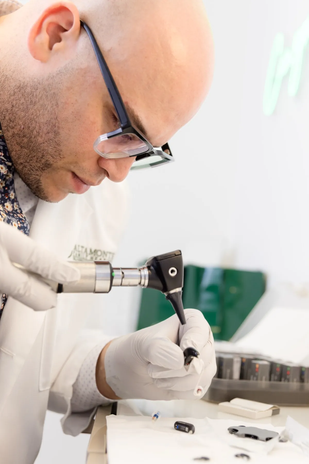 Jaysee at the repair bench, working on a hearing aid with a small tool
