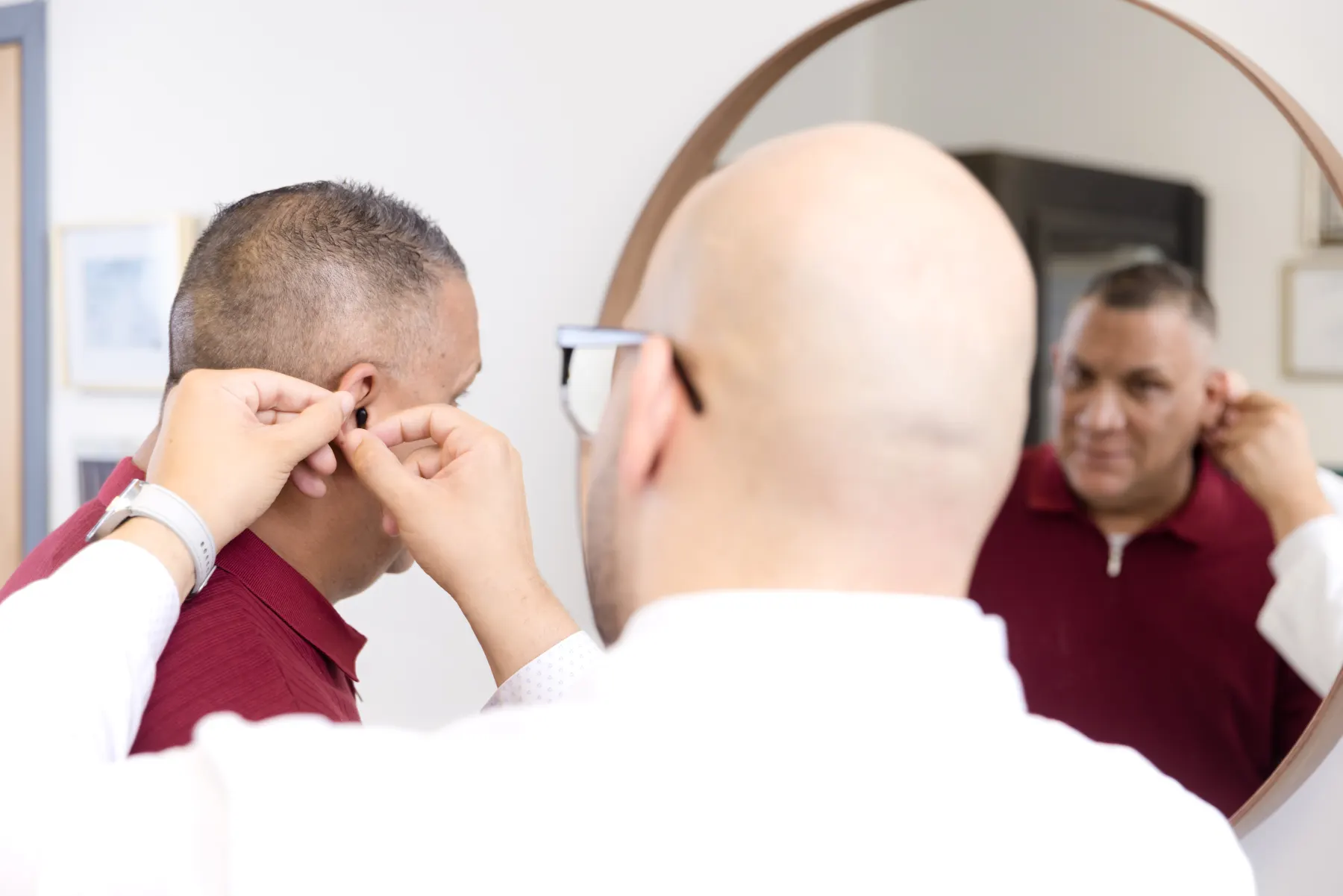 Jaysee fitting a hearing aid while the patient watches in the mirror