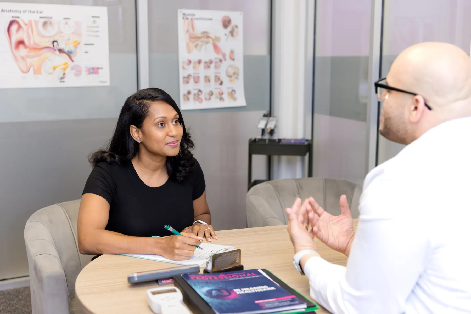 A patient taking notes as Jaysee explains her results at the consultation table