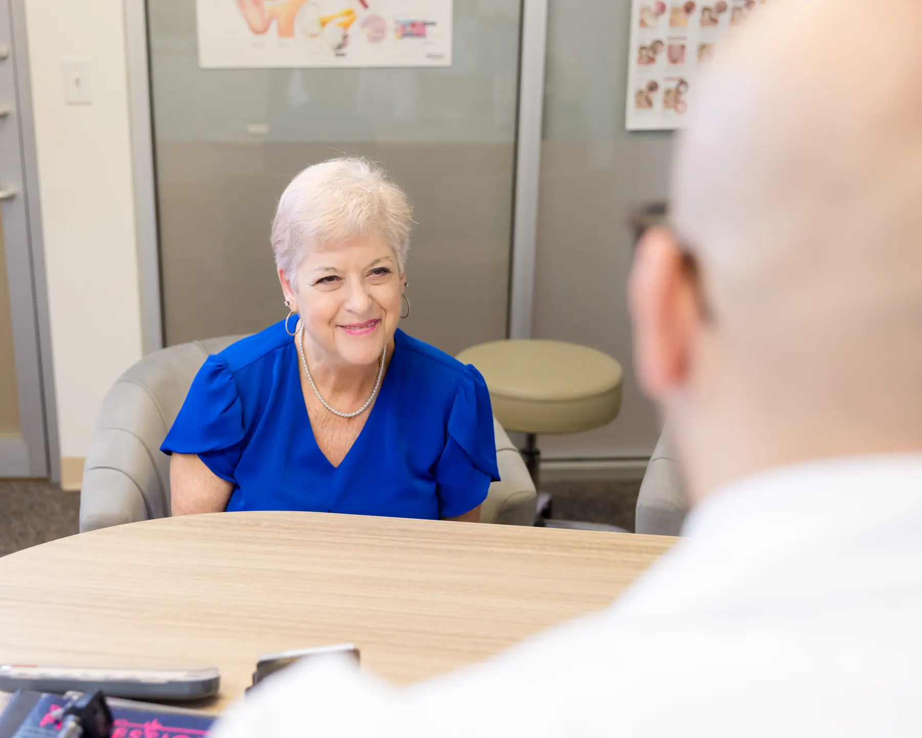 A patient smiling across the round table as Jaysee listens