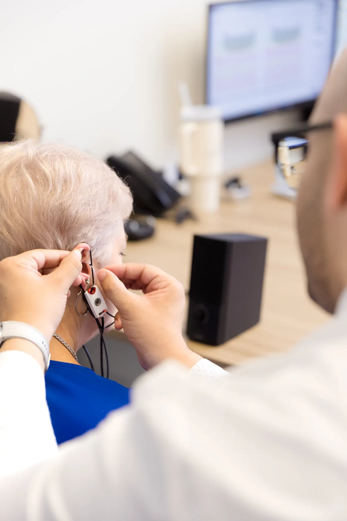 Jaysee placing the Real Ear Measurement probe in a patient's ear at his desk