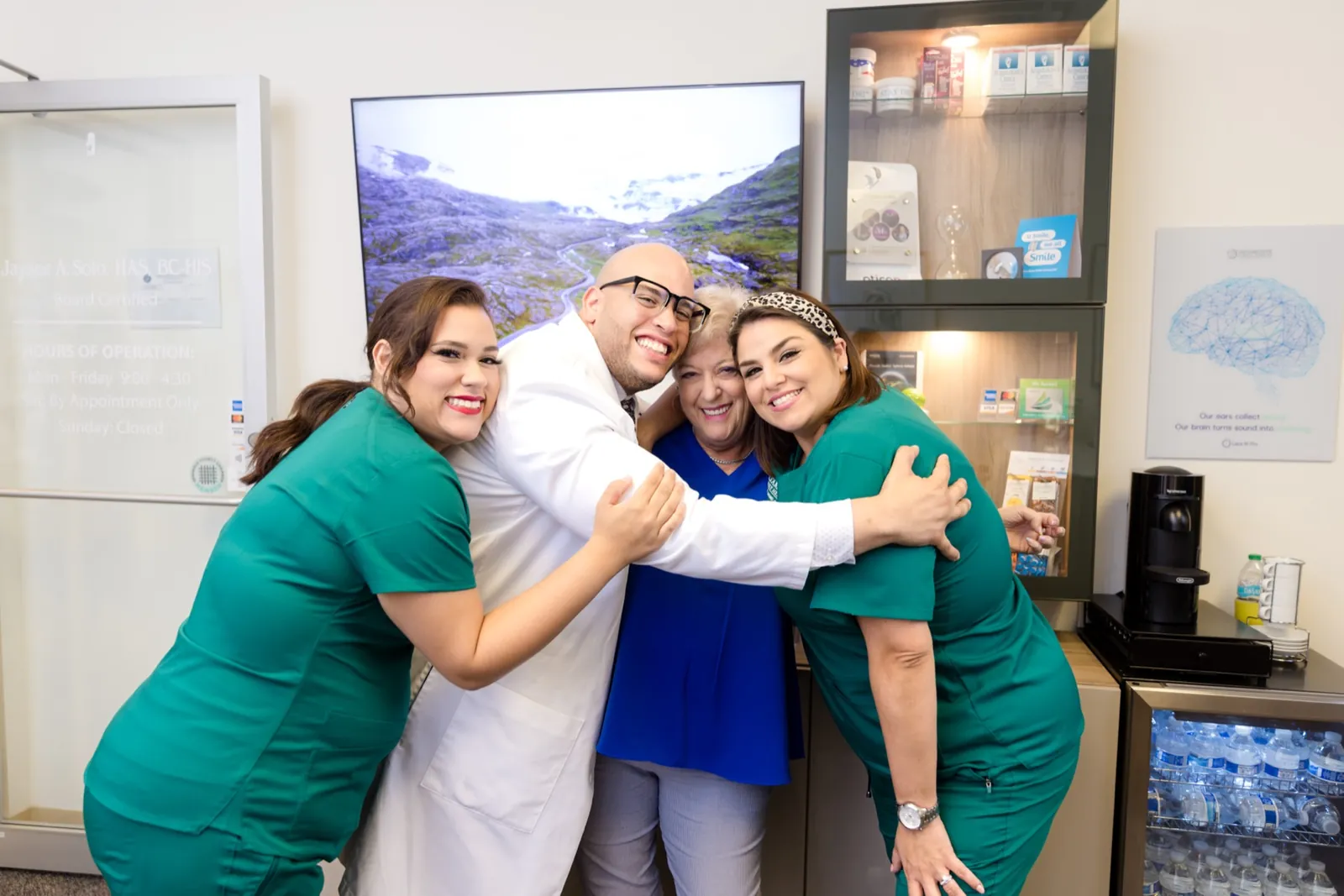 Jaysee, Grace and Francesca hugging a patient in the office